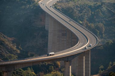 Yakıt tankeri ve yolda dolaşan birkaç araçla vadiden geçen büyük bir viyadük..