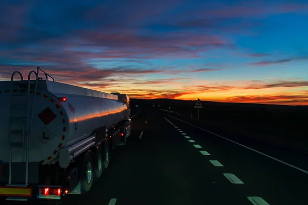 Fuel tanker truck driving on a highway at night.