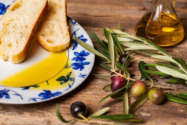 Biraz zeytin yağı ve zeytin dallarının yanında bir dilim ekmek ve bir yağ şişesi..