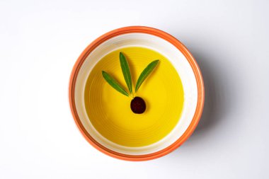 İçinde üç zeytin yaprağı olan zeytinyağlı bir kase..