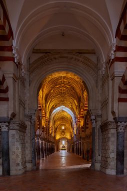 Sütunlar ve dekore edilmiş kemerler arasında Cordoba Katedrali 'nin içinde arka planda bir şapel manzaralı bir koridor..