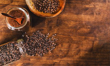 Tencere yalan söyleyip kahve çekirdeklerini ahşap bir masaya döküyor. Yanında da başka bir demlik, yanında da kahve ve daha fazla fasulye var..