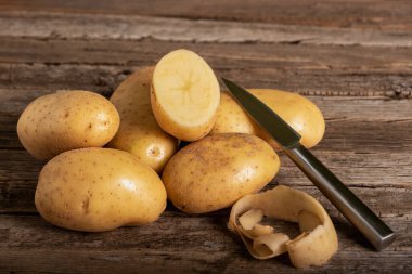 Kırsal bir ahşap masada patates yemek için, yanında da patates ve bıçak..
