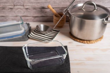 Bir tencere, bir kepçe ve başka bir yemek kabının yanında cam yemek kabı..