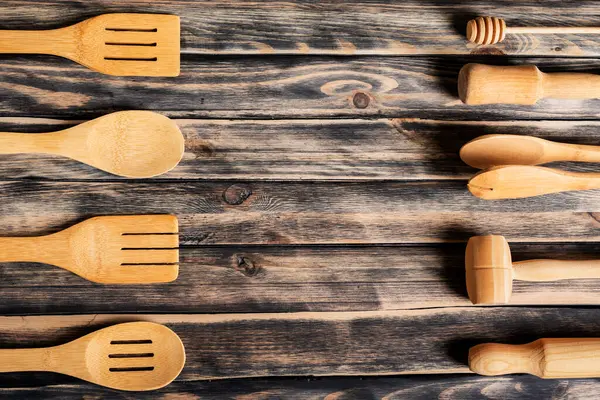 Tahta mutfak gereçleri, kaşıklar, maşalar, merdaneler gibi, görüntünün her iki tarafında, merkezi fotokopi alanı için terk eden, koyu ahşap arka planda.