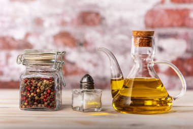 Ekstra saf zeytinyağı, tuzluk ve karabiber kavanozlu cam yağ kabuğu kırsal alanda hafif arka plan, gastronomik konsept..