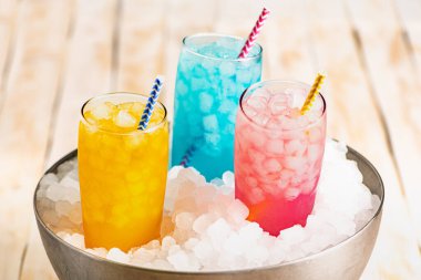 Bir kaç bardak buzlu ve çeşitli renklerde soda, buz gibi buzla dolu metal bir kasenin içinde..