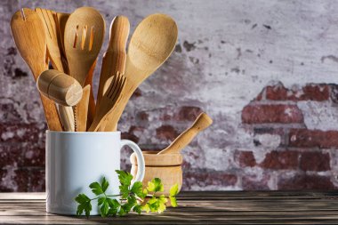 Beyaz seramik sürahi ahşap mutfak gereçleriyle dolu havan ve kırsal arka planda taze maydanoz..