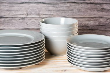 Tabakların ve kaselerin çeşitli boyutlarda olduğu beyaz sofra takımı, açık ahşap arka planda..