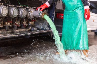 Uluslararası temizlik sertifikasını elde etmek için iç temizlik işlemi sırasında tankerden artık ve su boşaltan bir kamyon yıkama istasyonunda operatör..