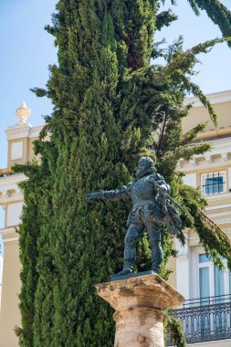 Valencia, İspanya - 12 Ağustos 2022: Estatua de Francisco Pizarro, Plaza de Manises 'de uzun bir selvi ve dekoratif bina cephesi önünde taş bir sütunun üzerinde duruyor..