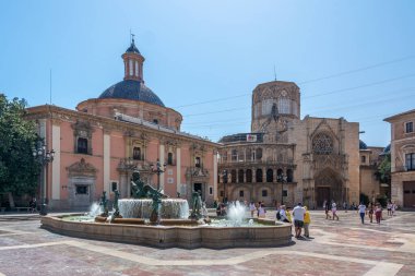 Valencia, İspanya - 12 Ağustos 2022: Turia Çeşmesi 'nin bronz heykelleri Plaza de la Virgen' deki Valencia Katedrali 'nin pembe cephesi ve Gotik portalının önünde yer almaktadır.