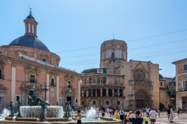 Valencia, İspanya - 12 Ağustos 2022: Turia Pembe Bazilika cephesi ve Valencia Katedrali 'nin açık mavi gökyüzü altında yer alan Gotik kapısı önünde bronz figürlü Turia Çeşmesi