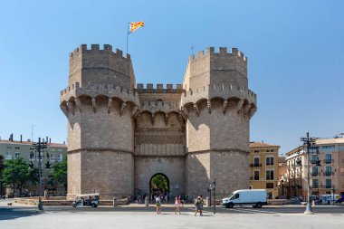 Valencia, İspanya - 12 Ağustos 2022: Eski şehrin girişindeki taş kemerlerin altından geçen ziyaretçilerle ortaçağ Serranos Kuleleri 'nin kapısı.