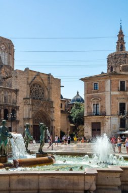 Valencia, İspanya - 12 Ağustos 2022: Turia Çeşmesi 'nin su jetleri Valencia Katedrali' nin Gotik portalı ve bazilikanın mavi kartonlu kubbesinden önce oyun oynuyorlar..