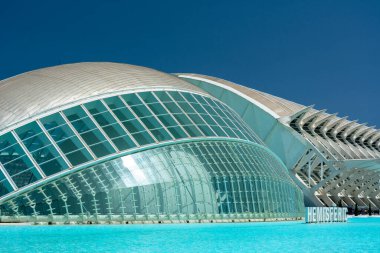 Valencia, İspanya - 12 Ağustos 2022: Hemisferic 'in Sanat ve Bilim Şehri' ndeki mimari görüşü, açık mavi gökyüzü altındaki yansıtıcı havuzu ve turistik faaliyetleri.
