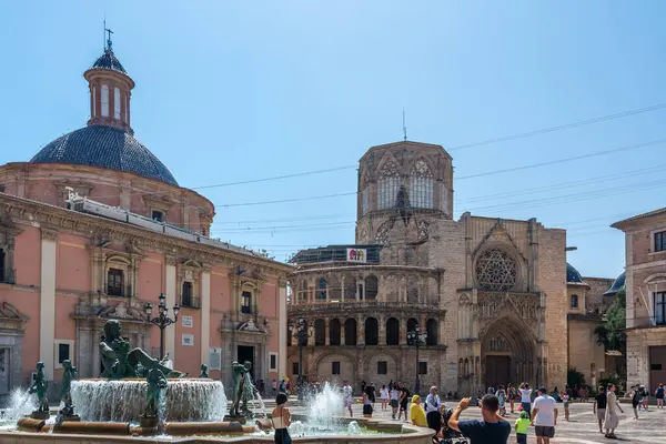 Valencia, İspanya - 12 Ağustos 2022: Turia Pembe Bazilika cephesi ve Valencia Katedrali 'nin açık mavi gökyüzü altında yer alan Gotik kapısı önünde bronz figürlü Turia Çeşmesi