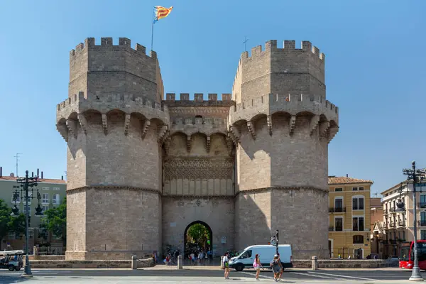 Valencia, İspanya - 12 Ağustos 2022: Eski şehrin girişindeki taş kemerlerin altından geçen ziyaretçilerle ortaçağ Serranos Kuleleri 'nin kapısı.