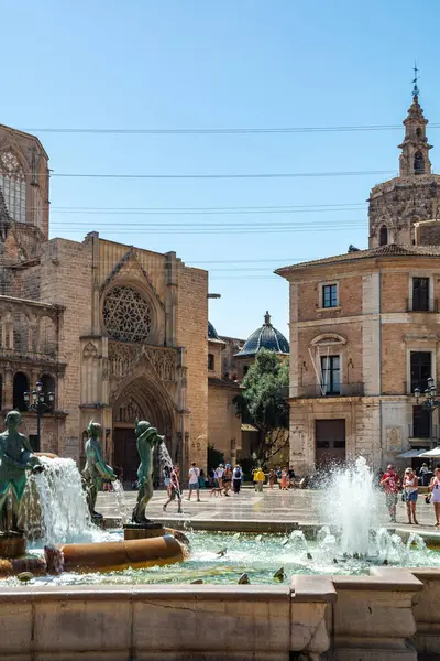 Valencia, İspanya - 12 Ağustos 2022: Turia Çeşmesi 'nin su jetleri Valencia Katedrali' nin Gotik portalı ve bazilikanın mavi kartonlu kubbesinden önce oyun oynuyorlar..
