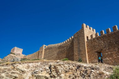 Ziyaretçiler, Teruel eyaletinin Albarracin kentindeki eski bir taş geçitten tırmanarak ortaçağ kalesinin duvarını keşfediyorlar..