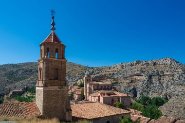 Kırmızı kiremitli çatıların panoramik manzarası ve Iglesia de Santiago Apostol çan kulesi berrak bir yaz gökyüzünün altındaki engebeli kireçtaşı uçurumlarına kurulmuş..