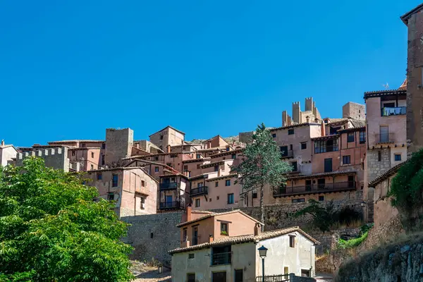 Katedralin fayanslı kulesi, açık mavi gökyüzünün altında, terracotta binalarının ve engebeli uçurumların üzerinde yükselir..