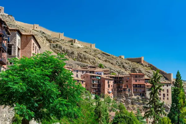 Katedralin fayanslı kulesi, açık mavi gökyüzünün altında, terracotta binalarının ve engebeli uçurumların üzerinde yükselir..