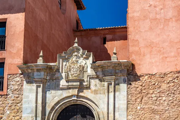 Katedralin fayanslı kulesi, açık mavi gökyüzünün altında, terracotta binalarının ve engebeli uçurumların üzerinde yükselir..