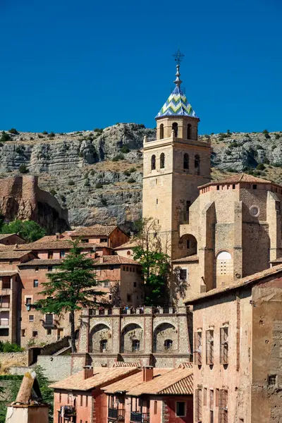 Kemerlerin ve terasotta çatılarının üzerinde yükselen açık mavi gökyüzünün altındaki Albarakin Katedrali 'nin geniş bir görüntüsü.