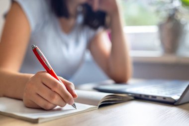 Not defterine yazan genç bir kız. Evde dizüstü bilgisayarla çalışan bir kadın. Masasında kalem ve defter olan liseli bir kız. İş kadını işte.