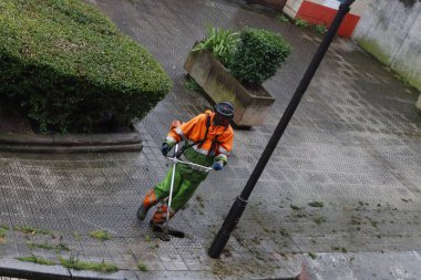 Elektrikli fırça keskisiyle sokaktaki çimleri kesiyor.