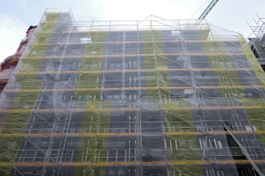 Bir binanın ön cephesinde çalışıyor.