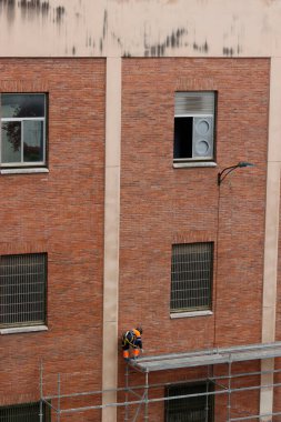 Bir binanın ön cephesinde çalışıyor.