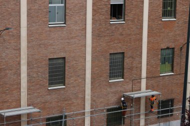 Bir binanın ön cephesinde çalışıyor.