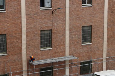 Bir binanın ön cephesinde çalışıyor.