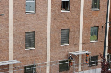 Bir binanın ön cephesinde çalışıyor.