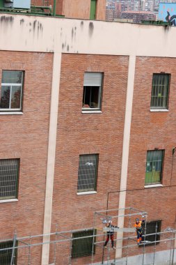 Bir binanın ön cephesinde çalışıyor.