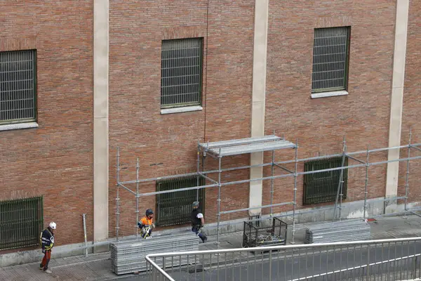 Bir binanın ön cephesinde çalışıyor.