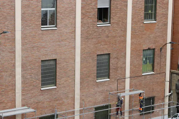 Bir binanın ön cephesinde çalışıyor.