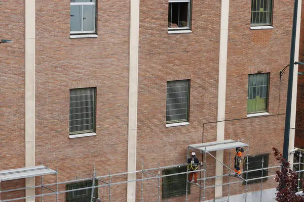 Bir binanın ön cephesinde çalışıyor.