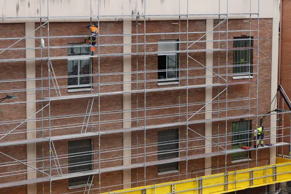 Bir binanın ön cephesinde çalışıyor.