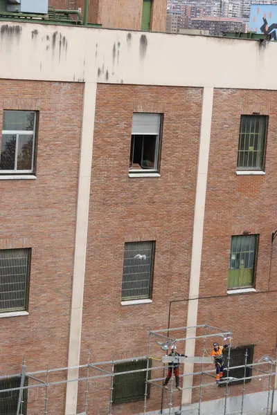 Bir binanın ön cephesinde çalışıyor.