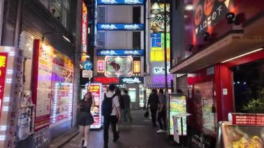 TOKYO, JAPONYAN 20 Mayıs 2025: Shinjuku 'nun aydınlık caddelerinde gece yürüyüşü, Tokyo' nun hareketli gece hayatı ve eğlence bölgesi.