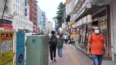 TOKYO, JAPONYAN 20 Mayıs 2025: Shinjuku 'nun hareketli caddelerinde gündüz yürüyüşü, Tokyo ticaret ve eğlence merkezi, Japonya' daki günlük şehir yaşamını yakalıyor.