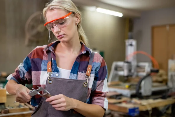 stock image woman worker carpenter or craftsman using vernier calipers measuring dimensions of woodwork. working wood design at workplace. wooden small business factory.