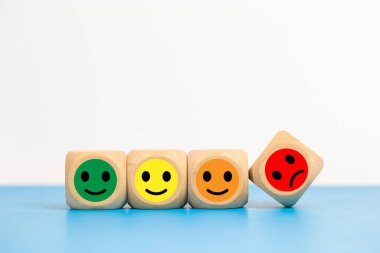 pozitif ve negatif duygularla yüzleş. Gülen suratlı tahta küp ve üzgün yüz ikonu. tatmin ve hizmet sıralaması.