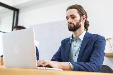 Buluşma odasında bilgisayar laptopu kullanan bıyıklı yakışıklı bir iş adamı. İşyerinde çalışan çekici bir iş adamı..