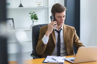 Akıllı iş adamı ofis masasında telefonla konuşuyor. Yönetici cep telefonundan konuşuyor. Yakışıklı müdür ofis masasında oturuyor..