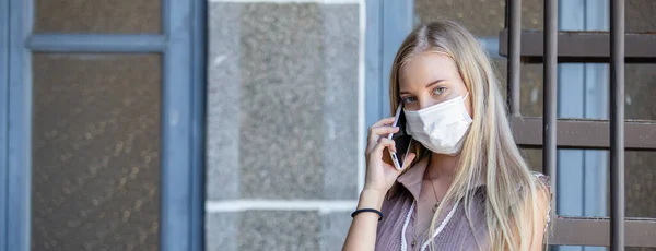 感染症の流行中に携帯電話のマスクを着用し 鼻や口から体内に侵入する可能性のあるほこりを防ぐために話す女性 — ストック写真