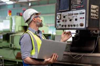 Industrial man man engineer wear uniform and helmet using laptop are checking system machine at factory. manager technician manufacturing. Workers industrial factory.